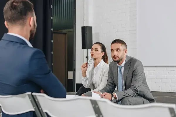 depositphotos_209196392-stock-photo-business-trainers-sitting-stage-documents