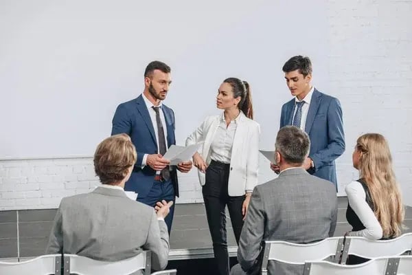 depositphotos_209197172-stock-photo-young-businesspeople-talking-documents-training