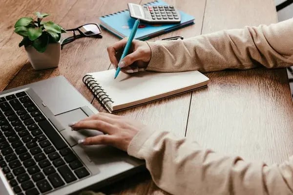 depositphotos_625049730-stock-photo-woman-typing-laptop-writing-notepad